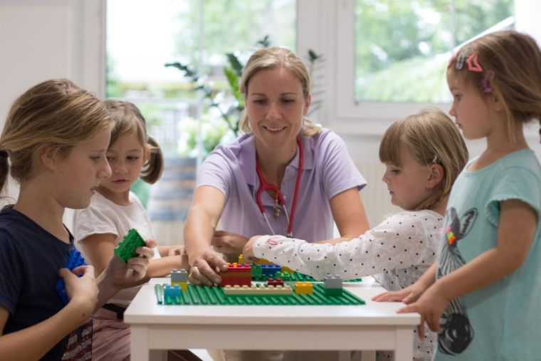 Ärztin baut im Wartezimmer mit vier Kindern an einer Lego-Platte